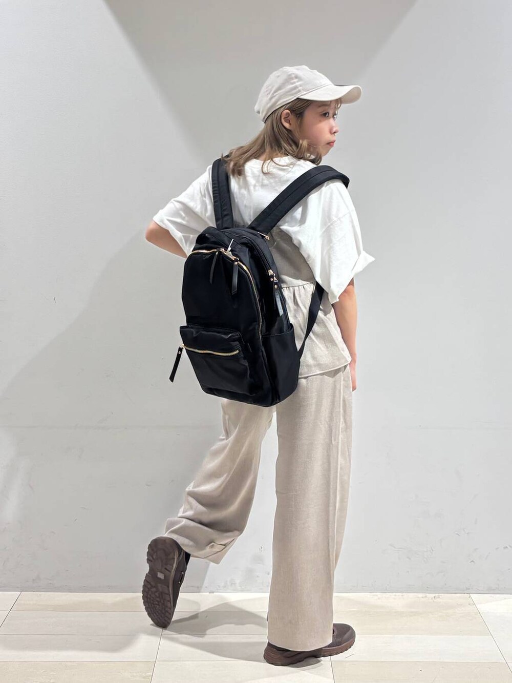 ブラウン系のスニーカー、ブラック系のバックパック/リュック、ベージュ系のサロペット/オーバーオールを着用したレディースの夏コーディネートの7枚目の写真