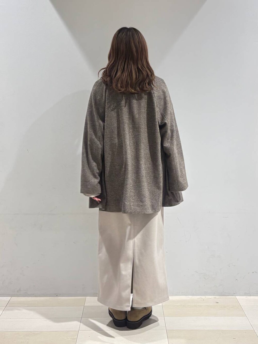 ブラウン系のチェスターコート、ベージュ系のローファー、ベージュ系のショルダーバッグを着用したレディースの秋コーディネートの3枚目の写真