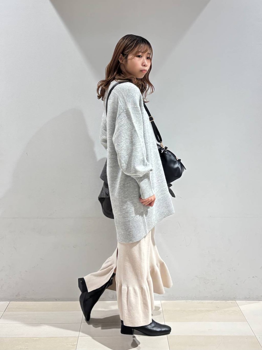ブラック系のショルダーバッグ、グレー系のチェスターコート、グレー系のニット/セーターを着用したレディースの冬コーディネートの9枚目の写真