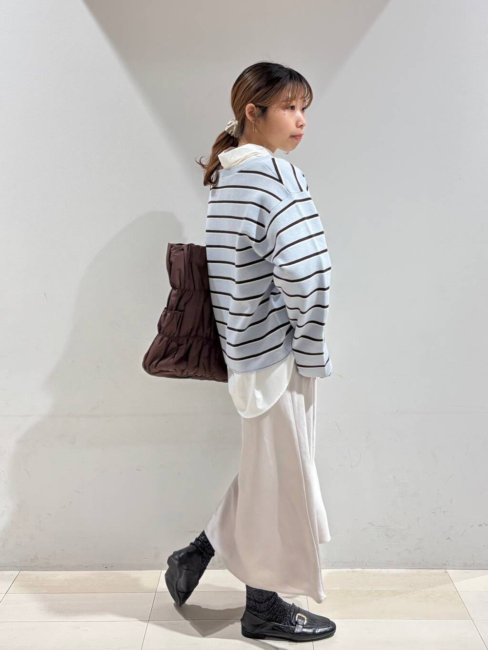 ブラック系のローファー、ブラウン系のトートバッグ、ブルー系のニット/セーターを着用したレディースの冬コーディネートの7枚目の写真