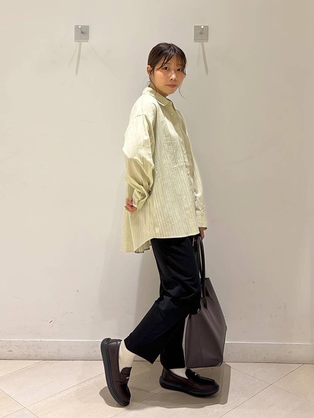 ブラック系のその他パンツ、ブラウン系のトートバッグ、ブラウン系のスニーカーを着用したレディースの春コーディネートの6枚目の写真