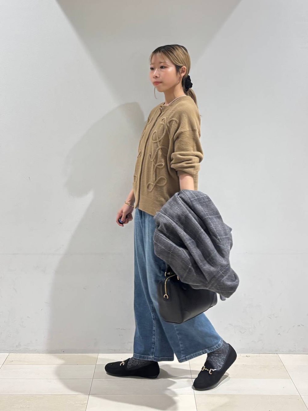 その他のチェスターコート、イエロー系のカーディガン/ボレロ、ブルー系のデニムパンツを着用したレディースの秋コーディネートの4枚目の写真