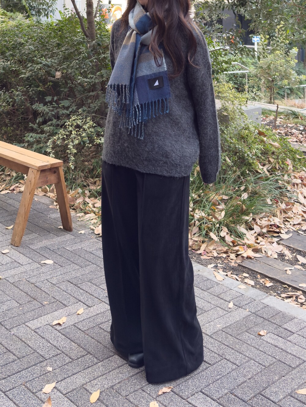 ブラック系のニット/セーター、ブラック系のスラックス、ブルー系のマフラーを着用したレディースの冬コーディネートの2枚目の写真