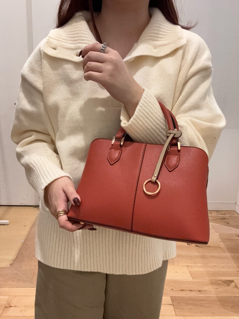 ゴールド系のバレエシューズ、オレンジ系のハンドバッグ、ホワイト系のニット/セーターを着用したレディースの冬コーディネートの2枚目の写真