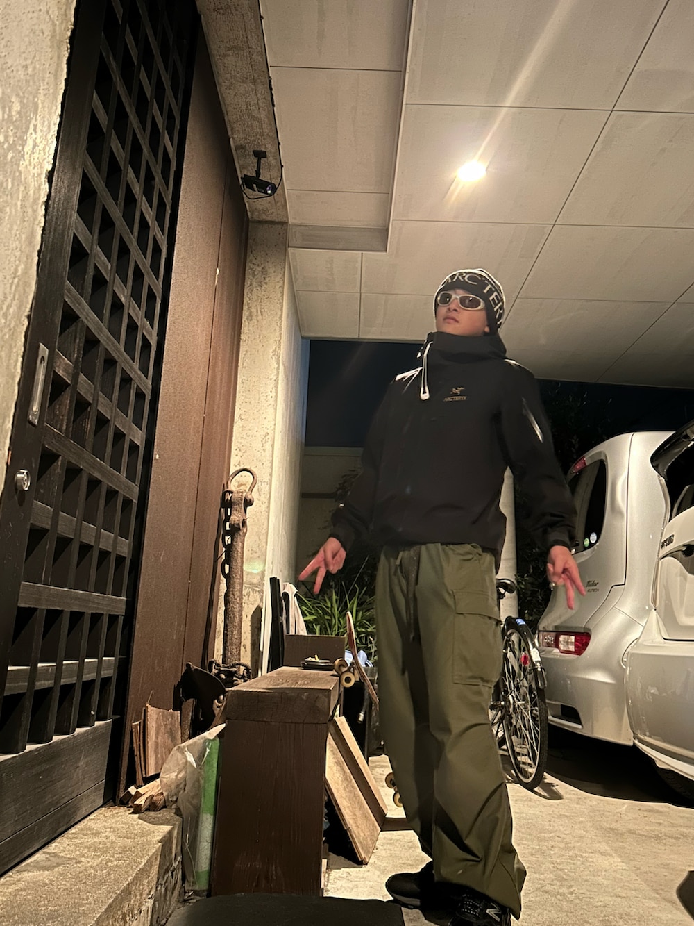 ブラック系のマウンテンパーカー、グリーン系のカーゴパンツ、ブラック系のスニーカーを着用したメンズの秋コーディネートの2枚目の写真