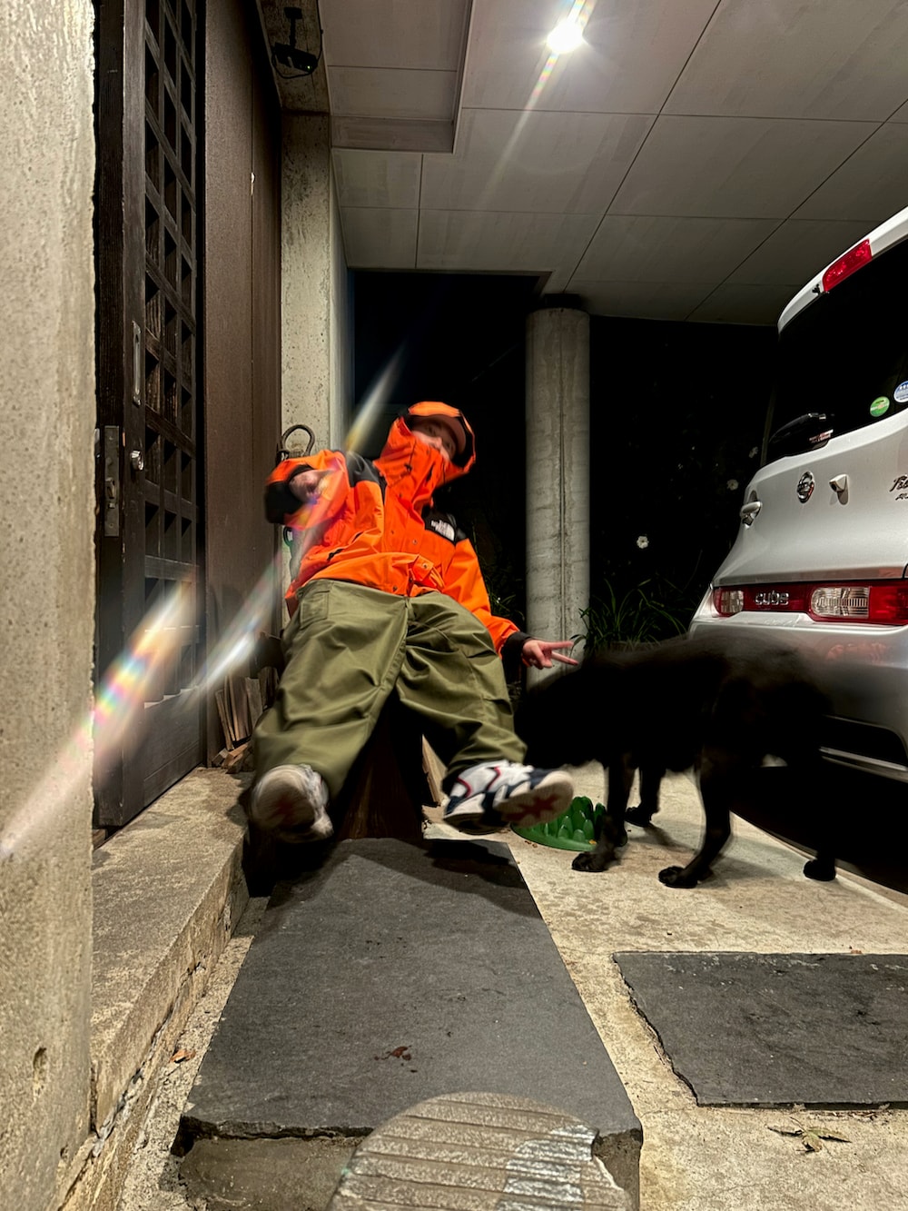 オレンジ系のマウンテンパーカー、グリーン系のカーゴパンツ、その他のスニーカーを着用したメンズの秋コーディネートの2枚目の写真