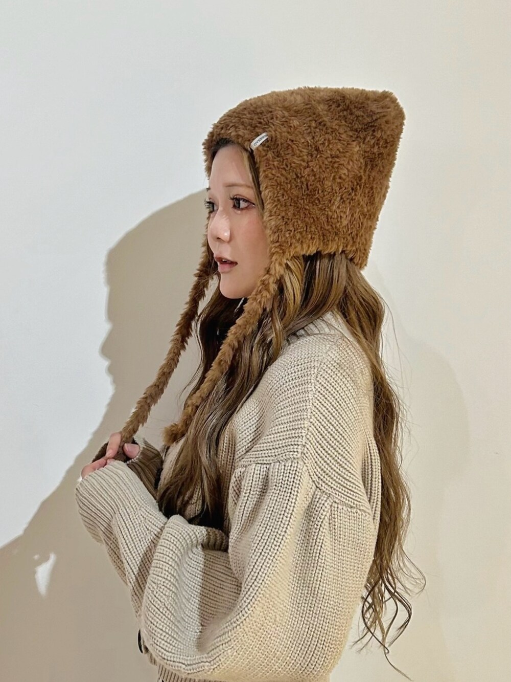 ブラウン系のニットキャップ/ビーニーを着用したレディースの秋コーディネートの2枚目の写真