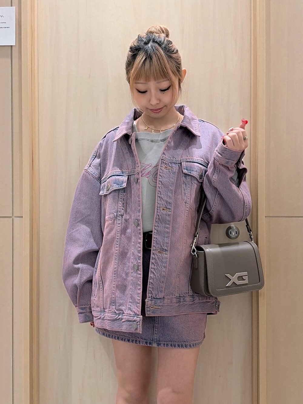 ピンク系のデニムジャケット、ピンク系のデニムスカート、ブラウン系のショルダーバッグを着用したレディースの冬コーディネートの3枚目の写真