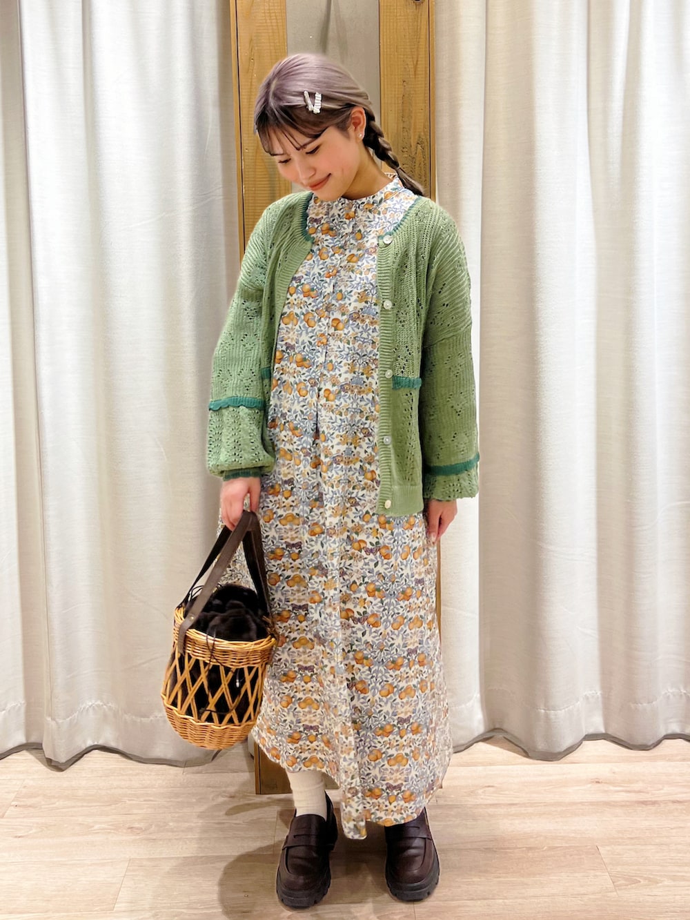 オレンジ系のワンピース、グリーン系のカーディガン/ボレロを着用したレディースの冬コーディネートの3枚目の写真