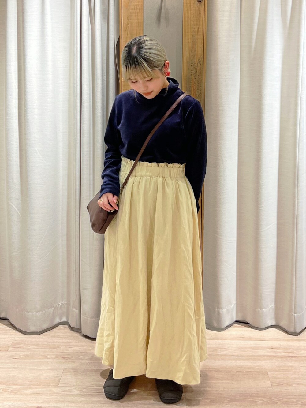 イエロー系のスカート、ブラウン系のハンドバッグ、ブルー系のTシャツ/カットソーを着用したレディースの秋コーディネートの2枚目の写真