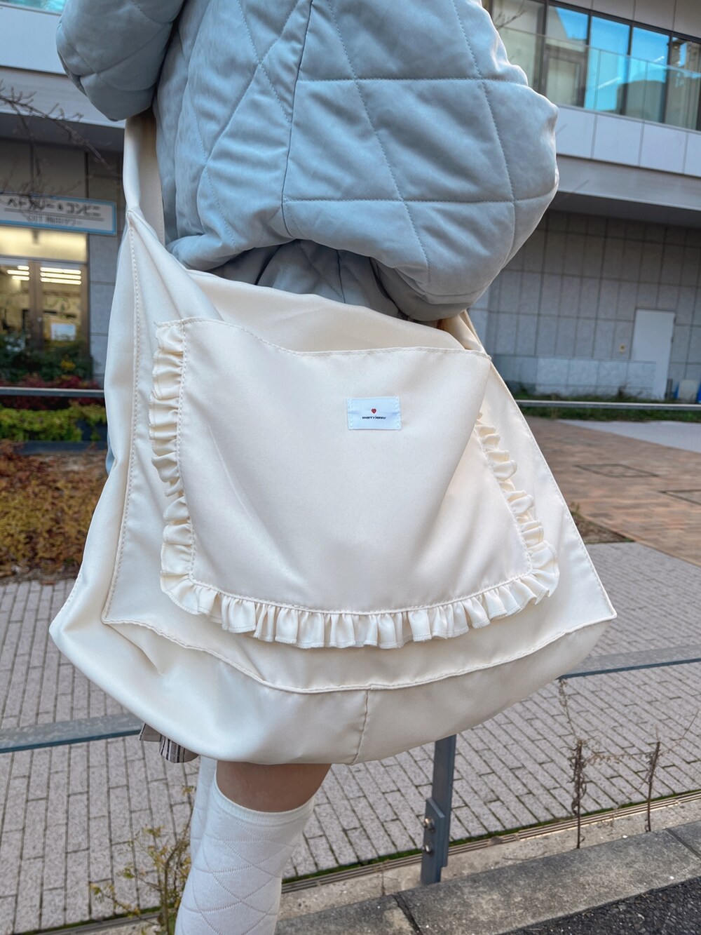 ブルー系のダウンジャケット/コート、ベージュ系のスカート、ホワイト系のトートバッグを着用したレディースの冬コーディネートの7枚目の写真