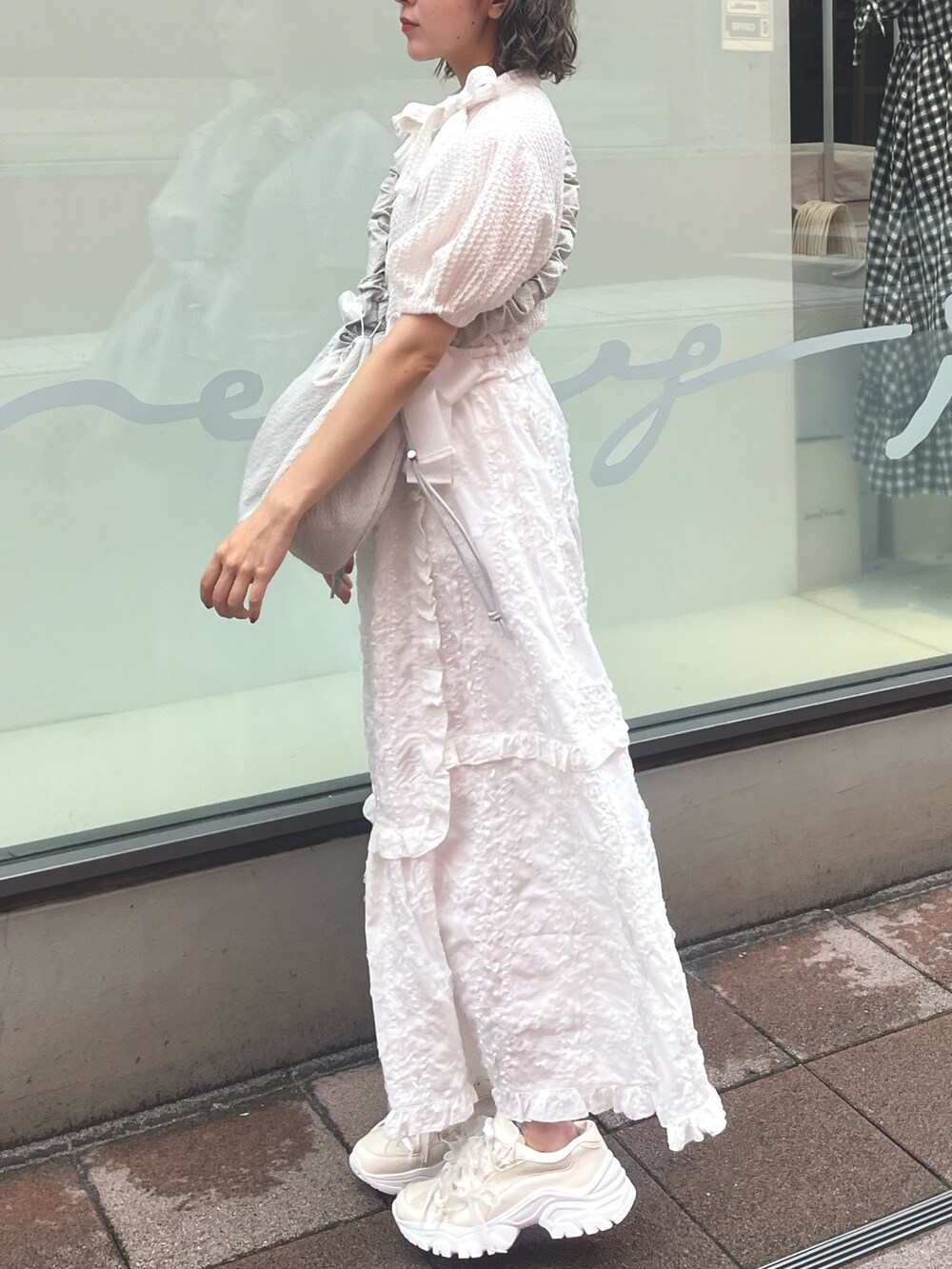 ホワイト系のスカート、ホワイト系のシャツ/ブラウス、グリーン系のショルダーバッグを着用したレディースの夏コーディネートの2枚目の写真