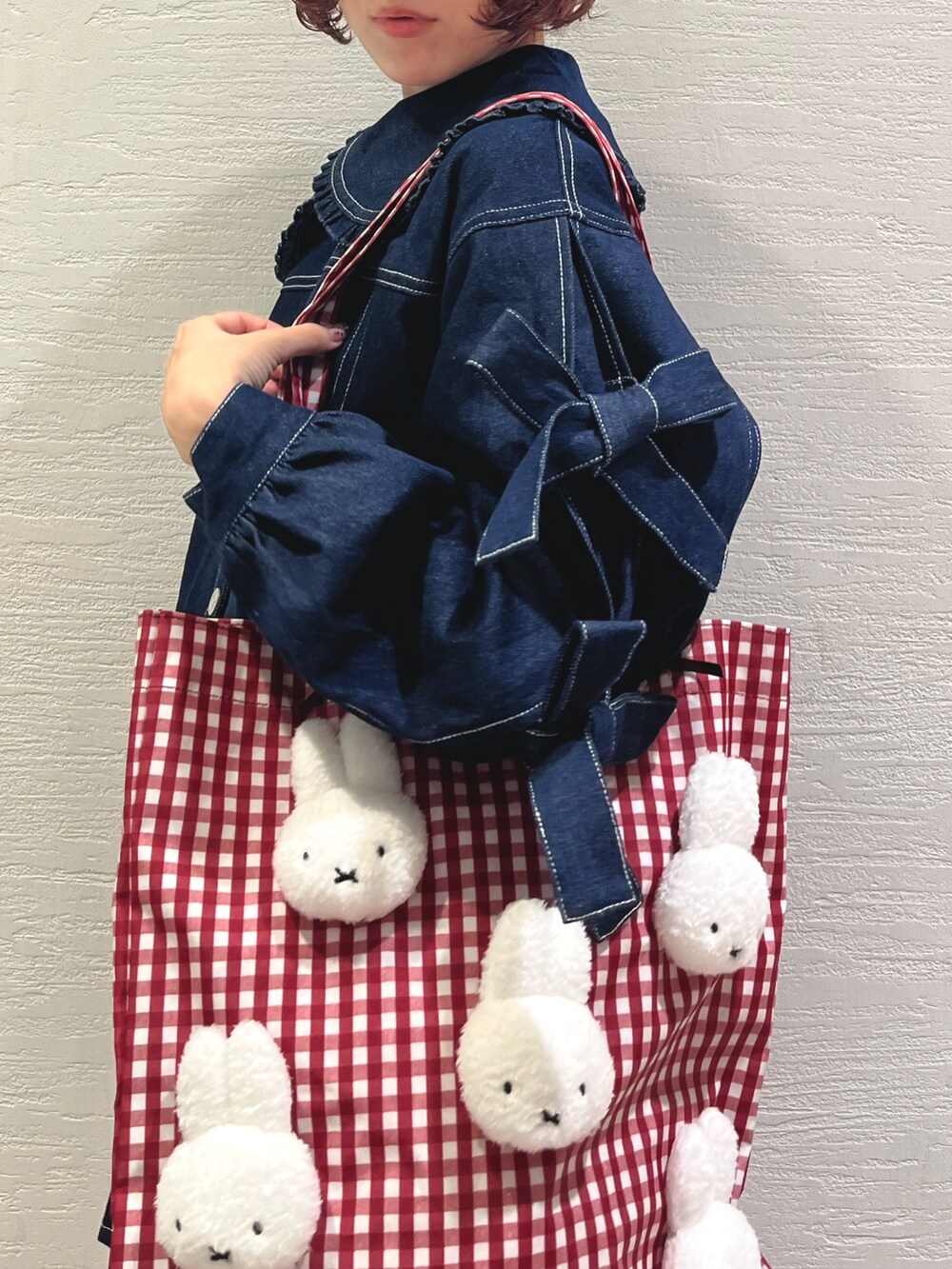 ブルー系のスカート、ブルー系のデニムジャケット、レッド系のトートバッグを着用したレディースの秋コーディネートの6枚目の写真