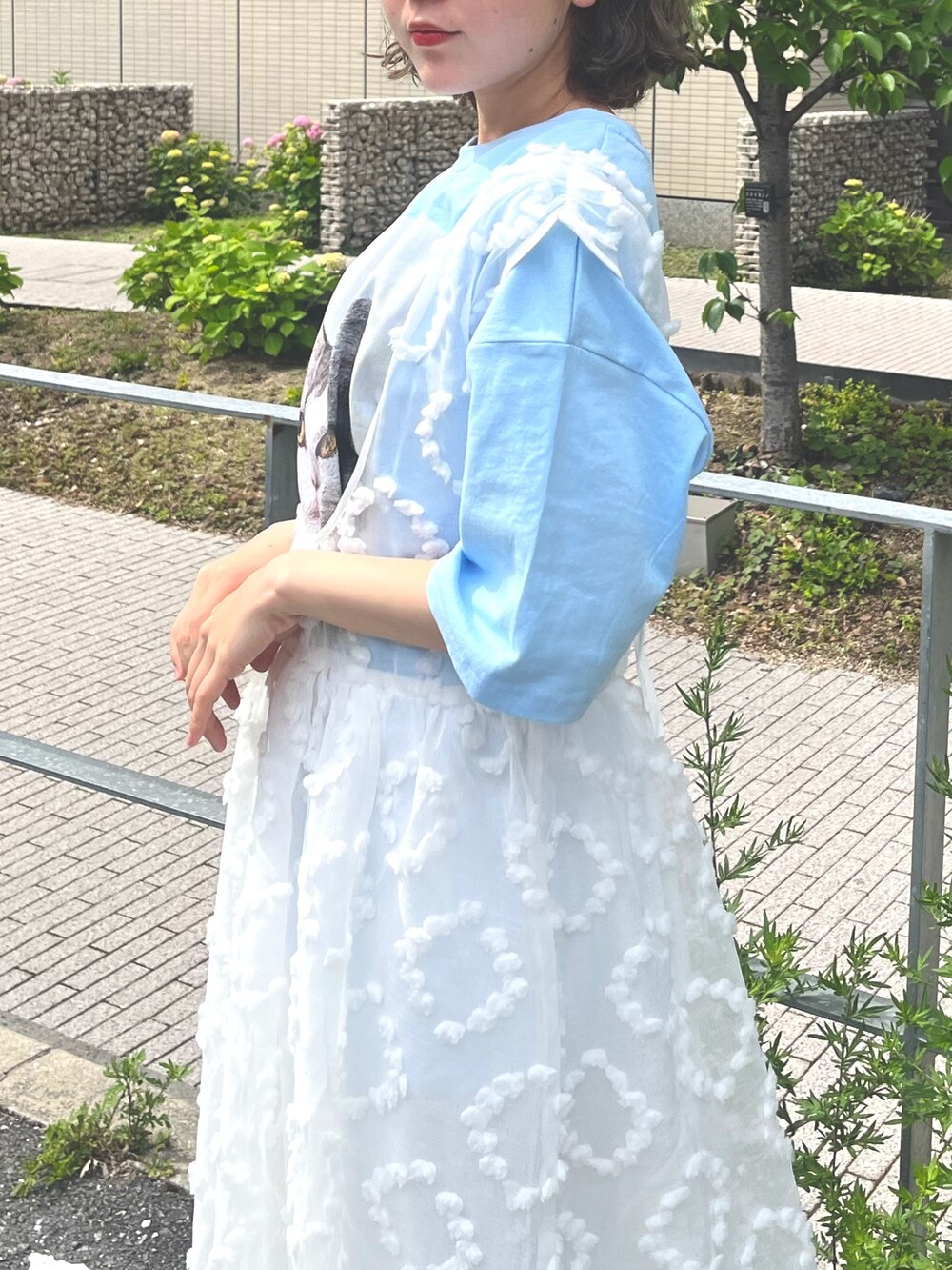 ホワイト系のジャンパースカート、ブルー系のTシャツ/カットソー、ブルー系のデニムパンツを着用したレディースの春コーディネートの6枚目の写真