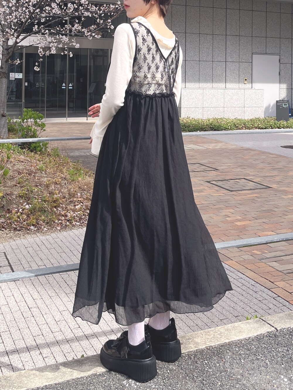 ホワイト系のTシャツ/カットソー、ブラック系のワンピース、ブラック系のスニーカーを着用したレディースの春コーディネートの4枚目の写真