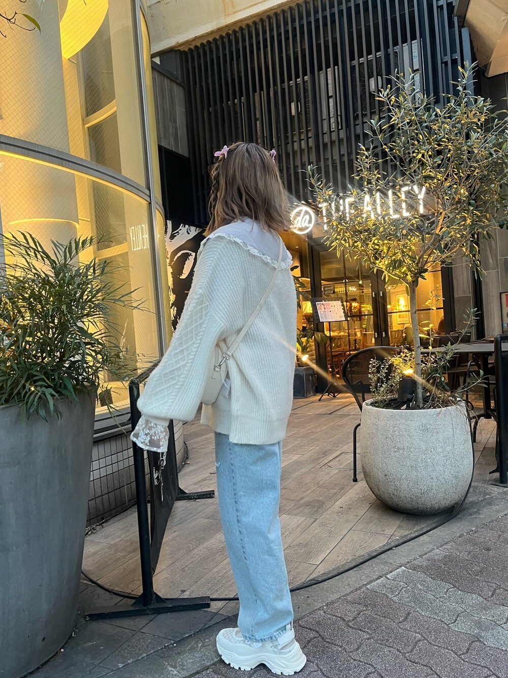 ホワイト系のショルダーバッグ、ホワイト系のニット/セーター、ブルー系のシャツ/ブラウスを着用したレディースの冬コーディネートの2枚目の写真