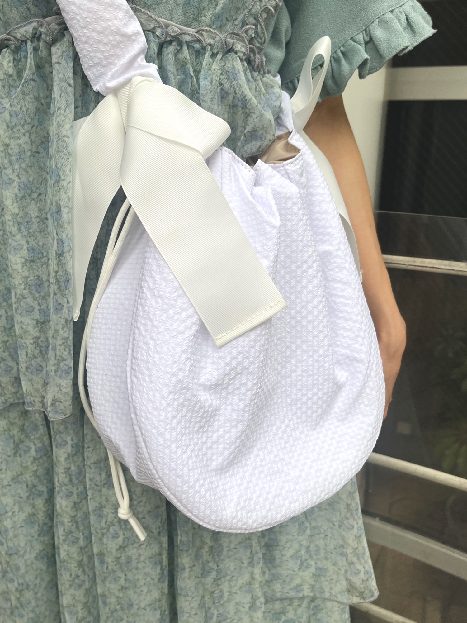 ホワイト系のショルダーバッグ、ブルー系のワンピース、グリーン系のワンピースを着用したレディースの夏コーディネートの8枚目の写真