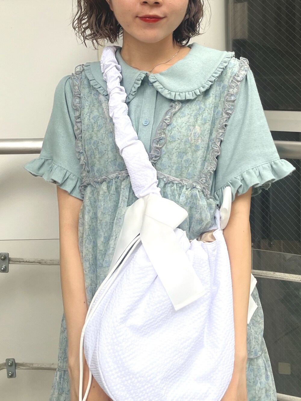 ホワイト系のショルダーバッグ、ブルー系のワンピース、グリーン系のワンピースを着用したレディースの夏コーディネートの4枚目の写真