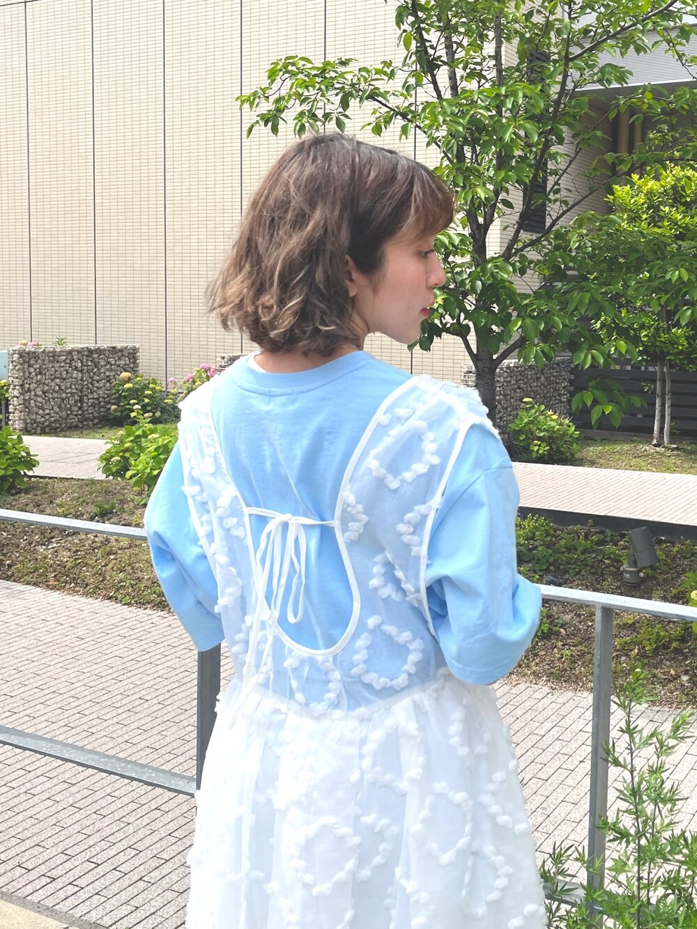 ホワイト系のジャンパースカート、ブルー系のTシャツ/カットソー、ブルー系のデニムパンツを着用したレディースの春コーディネートの7枚目の写真