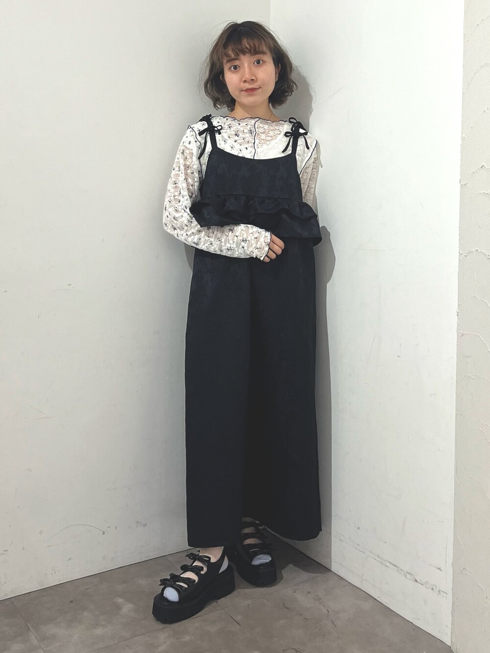 ブラック系のワンピース、ホワイト系のTシャツ/カットソー、ブラック系のサンダルを着用したレディースの春コーディネートの2枚目の写真