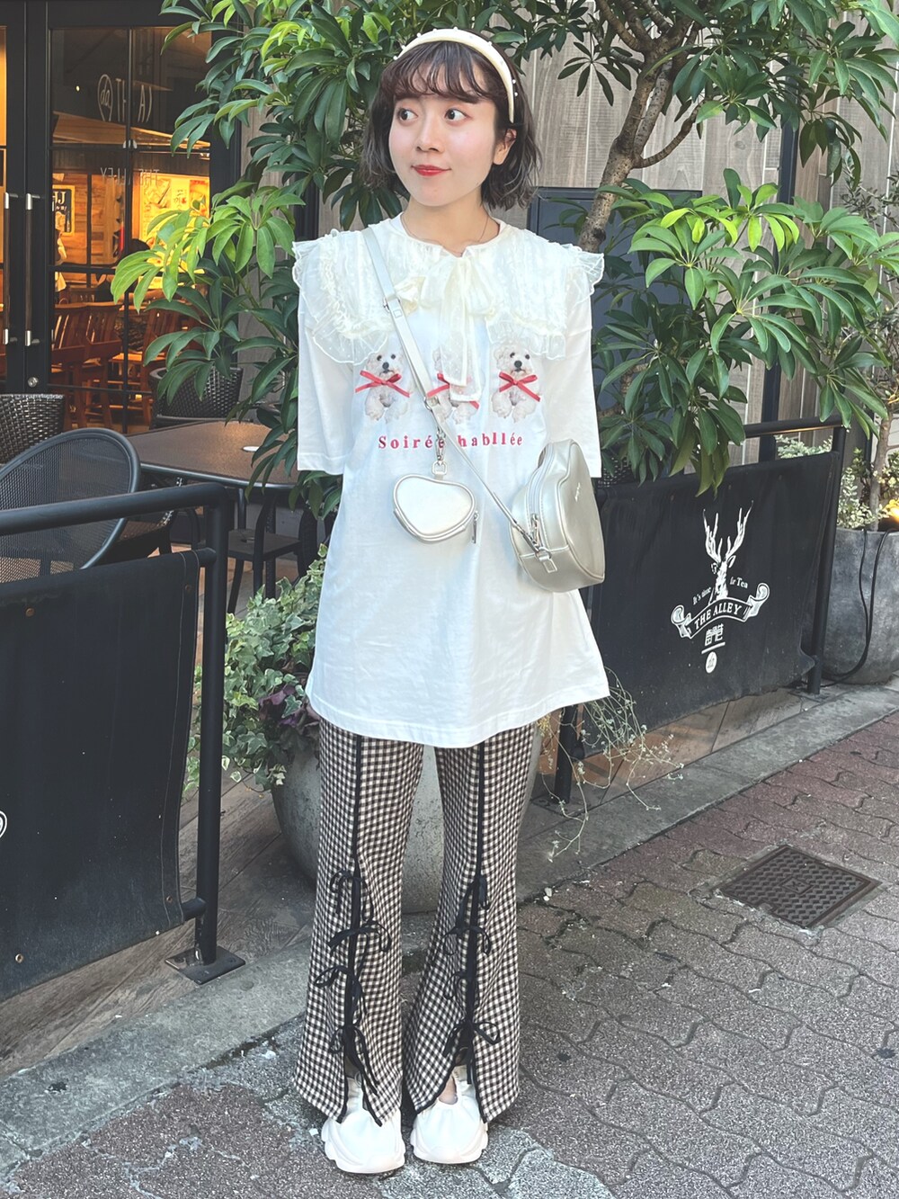 ホワイト系のTシャツ/カットソー、ゴールド系のショルダーバッグ、ブラウン系のスラックスを着用したレディースの夏コーディネートの2枚目の写真