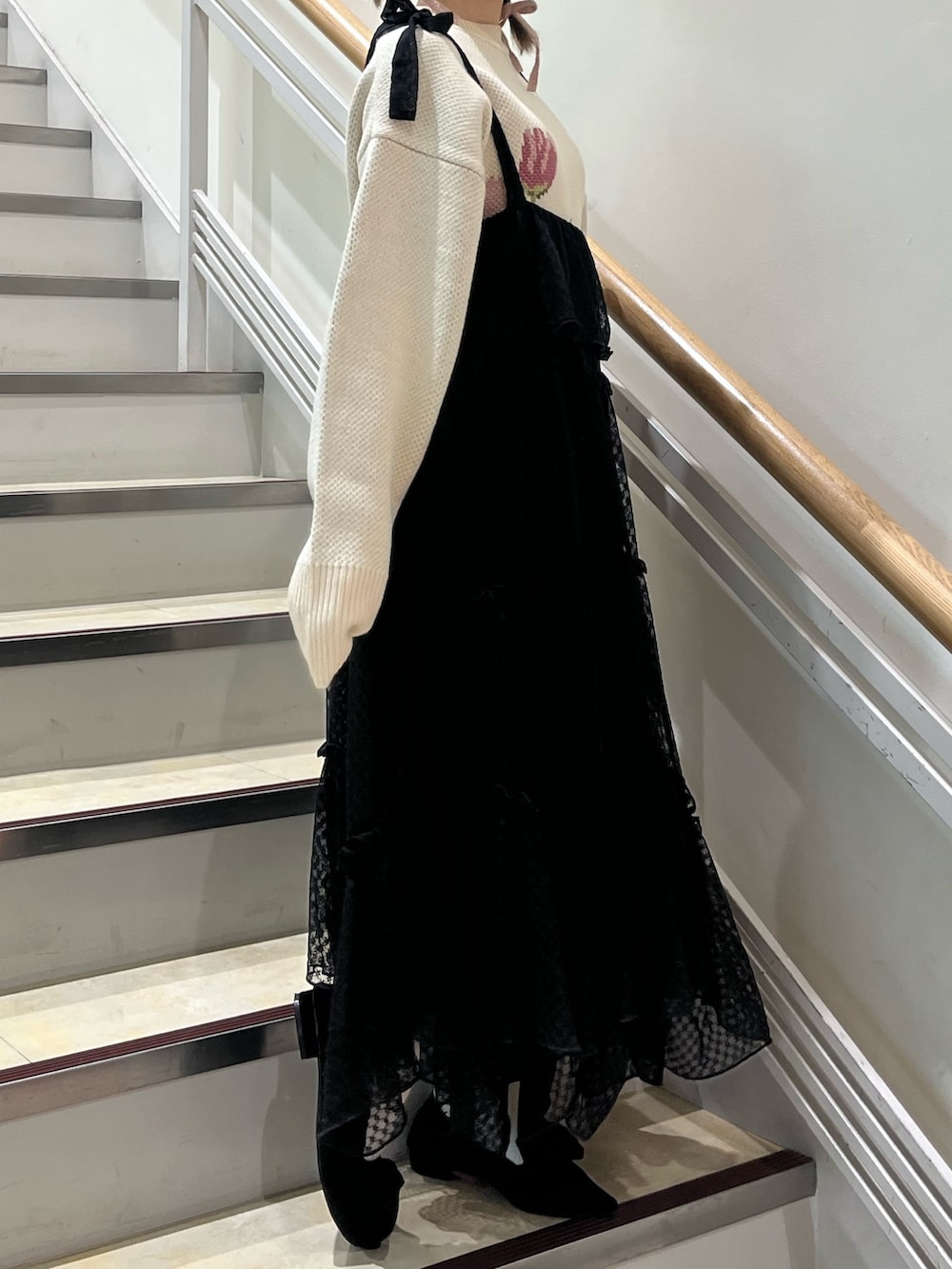 ブラック系のワンピース、ホワイト系のニット/セーター、ブラック系のパンプスを着用したレディースの冬コーディネートの3枚目の写真