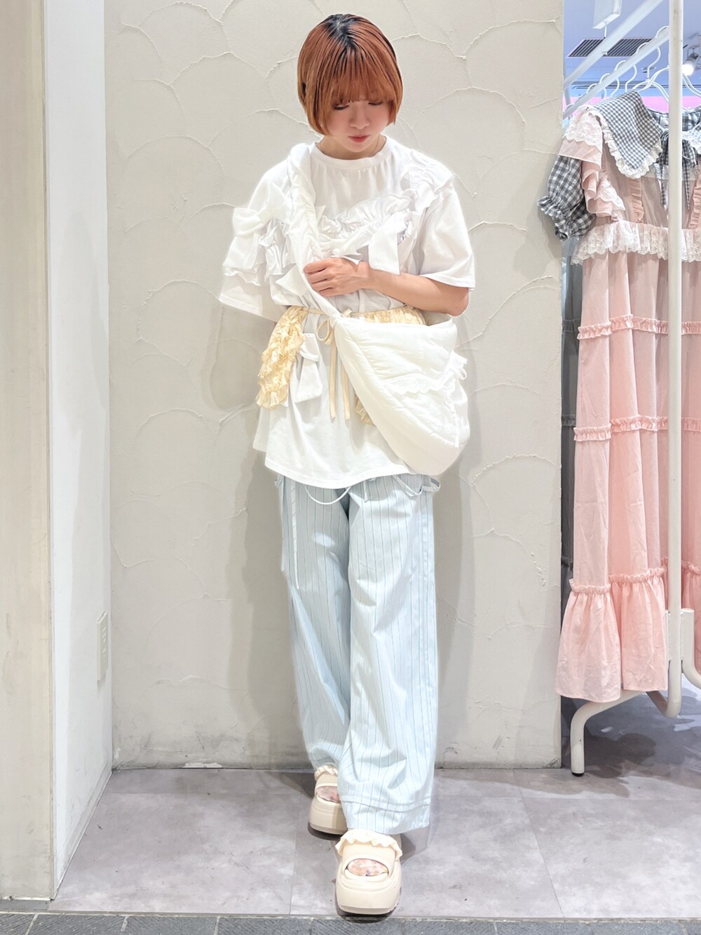 ホワイト系のショルダーバッグ、ホワイト系のTシャツ/カットソー、ブルー系のスラックスを着用したレディースの夏コーディネートの2枚目の写真