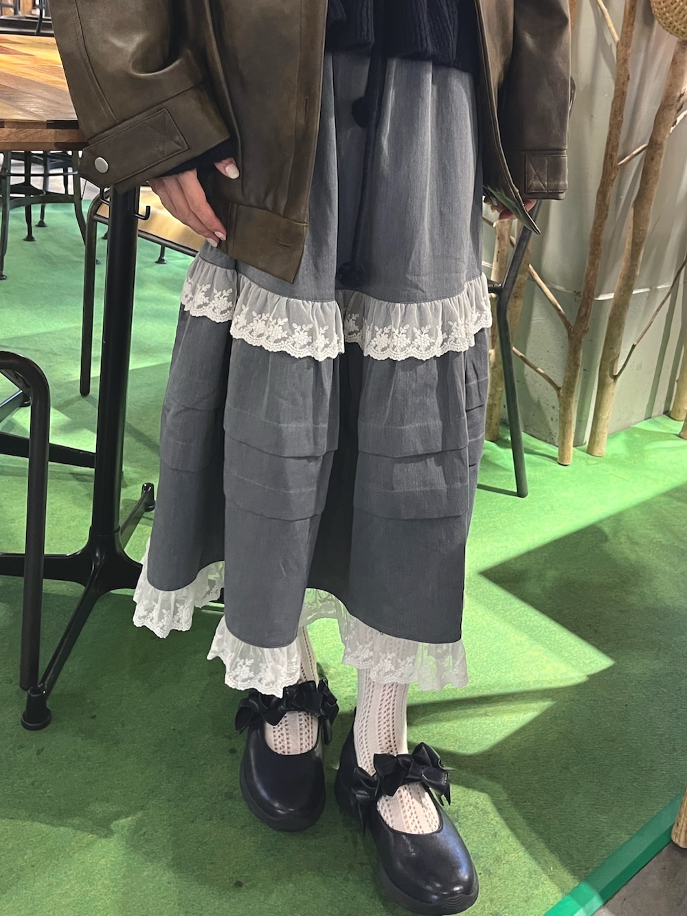 ブラウン系のブルゾン、ブルー系のニット/セーター、グレー系のスカートを着用したレディースの秋コーディネートの9枚目の写真