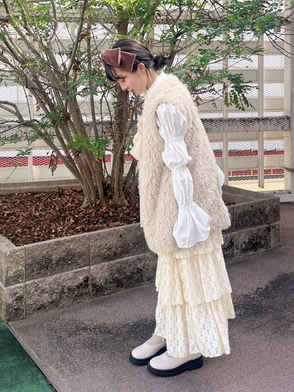 ベージュ系のダウンベスト、ホワイト系のシャツ/ブラウス、ホワイト系のスカートを着用したレディースの秋コーディネートの3枚目の写真