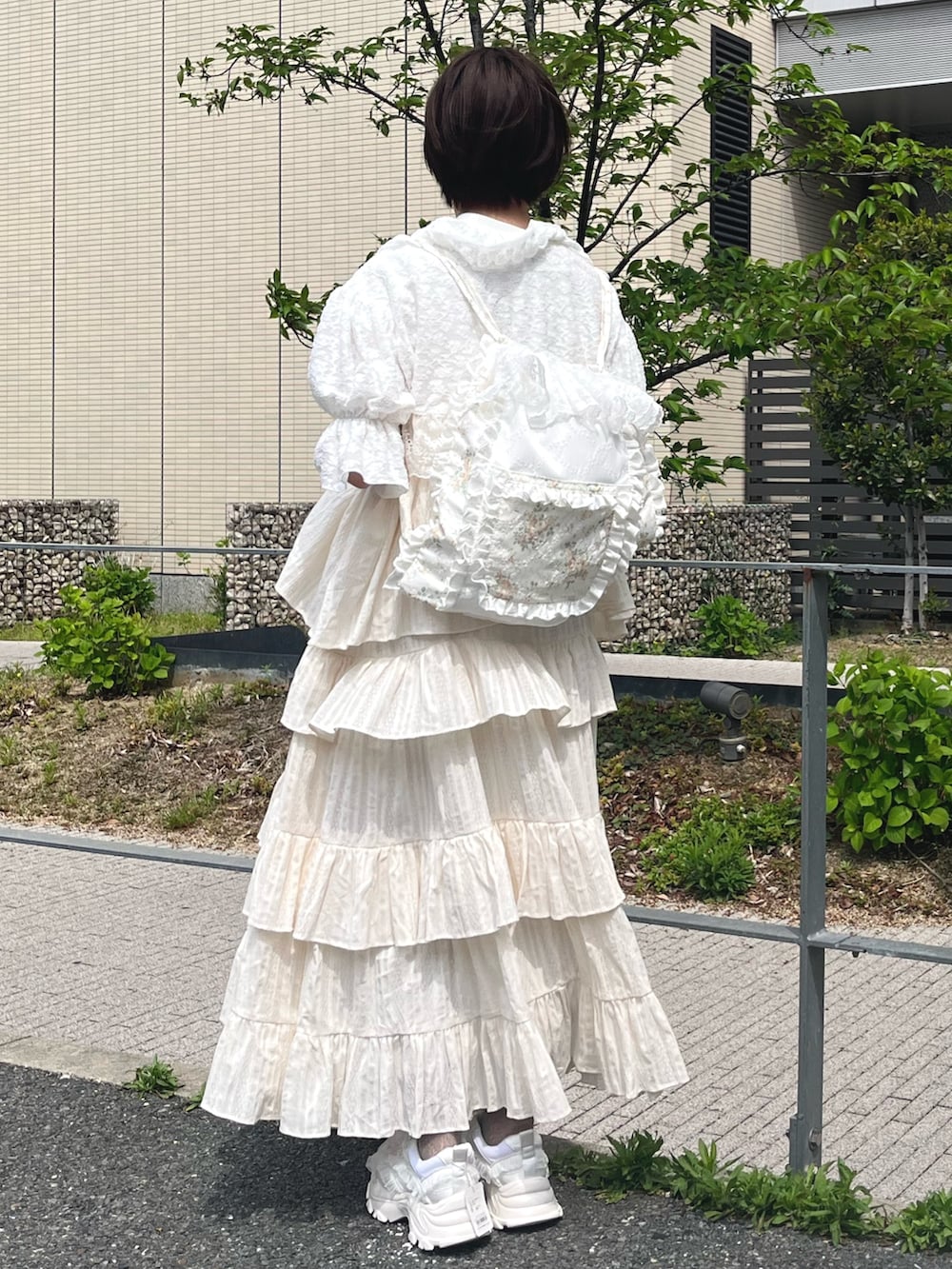 ホワイト系のスニーカー、イエロー系のバックパック/リュック、ホワイト系のカーディガン/ボレロを着用したレディースの春コーディネートの3枚目の写真