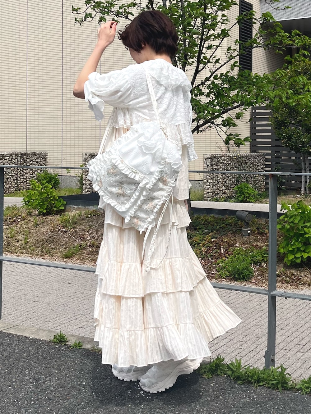 ホワイト系のスニーカー、イエロー系のバックパック/リュック、ホワイト系のカーディガン/ボレロを着用したレディースの春コーディネートの2枚目の写真