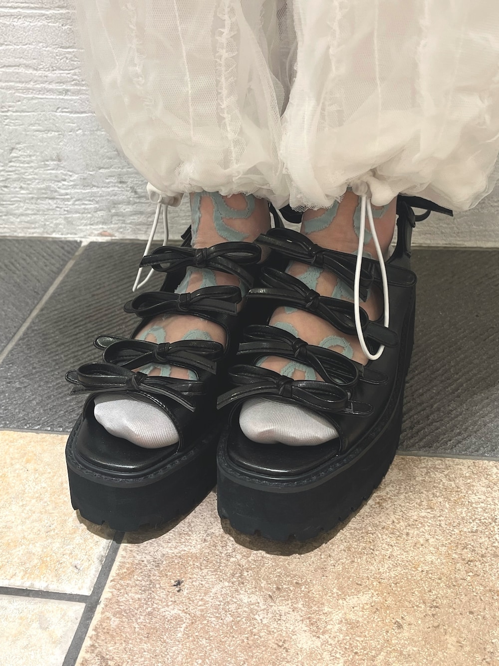 ホワイト系のスカート、ホワイト系のカーゴパンツ、ブラック系のサンダルを着用したレディースの春コーディネートの9枚目の写真