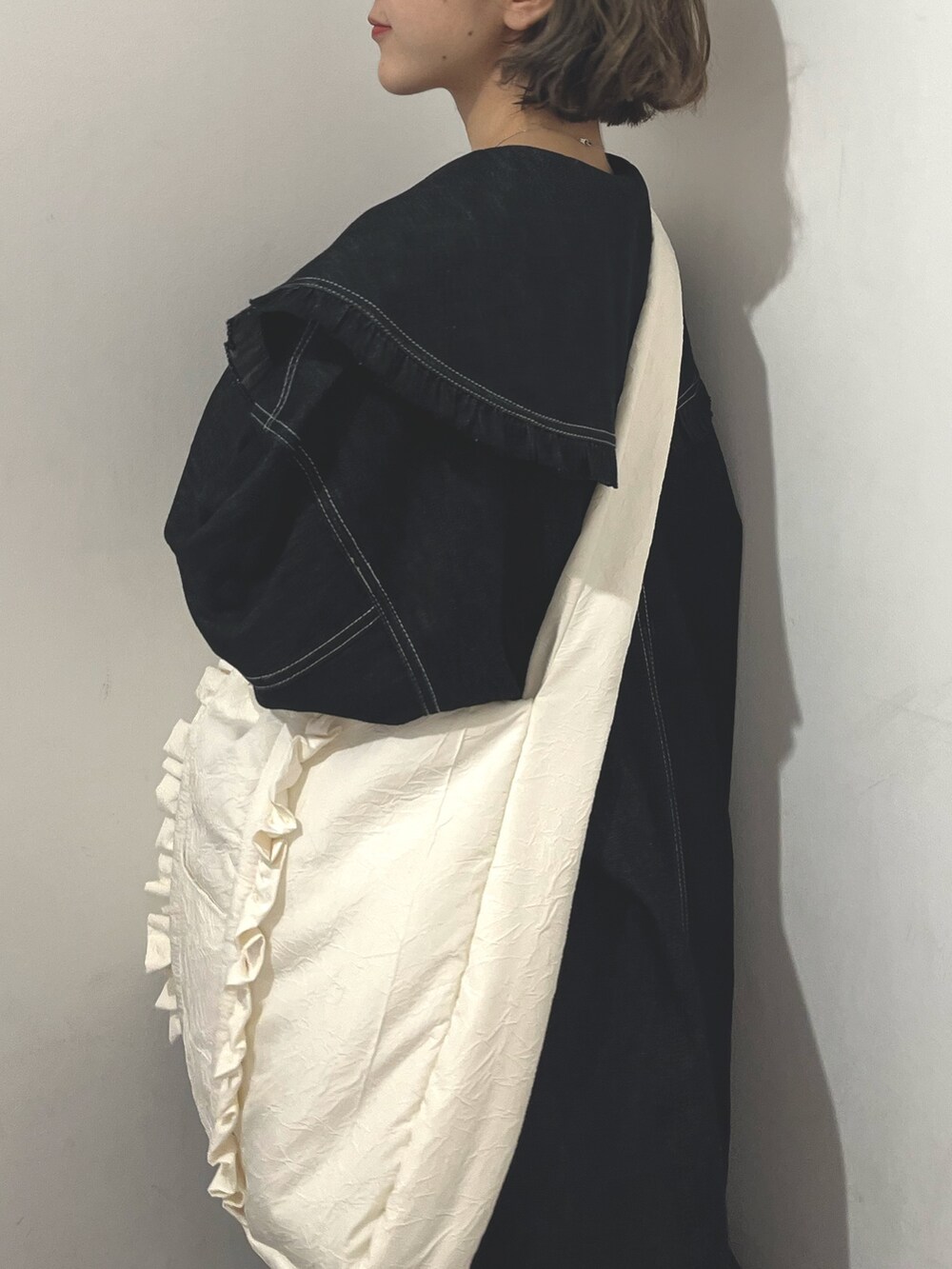 ホワイト系のトートバッグ、ブルー系のデニムジャケット、ブラック系のスカートを着用したレディースの秋コーディネートの7枚目の写真