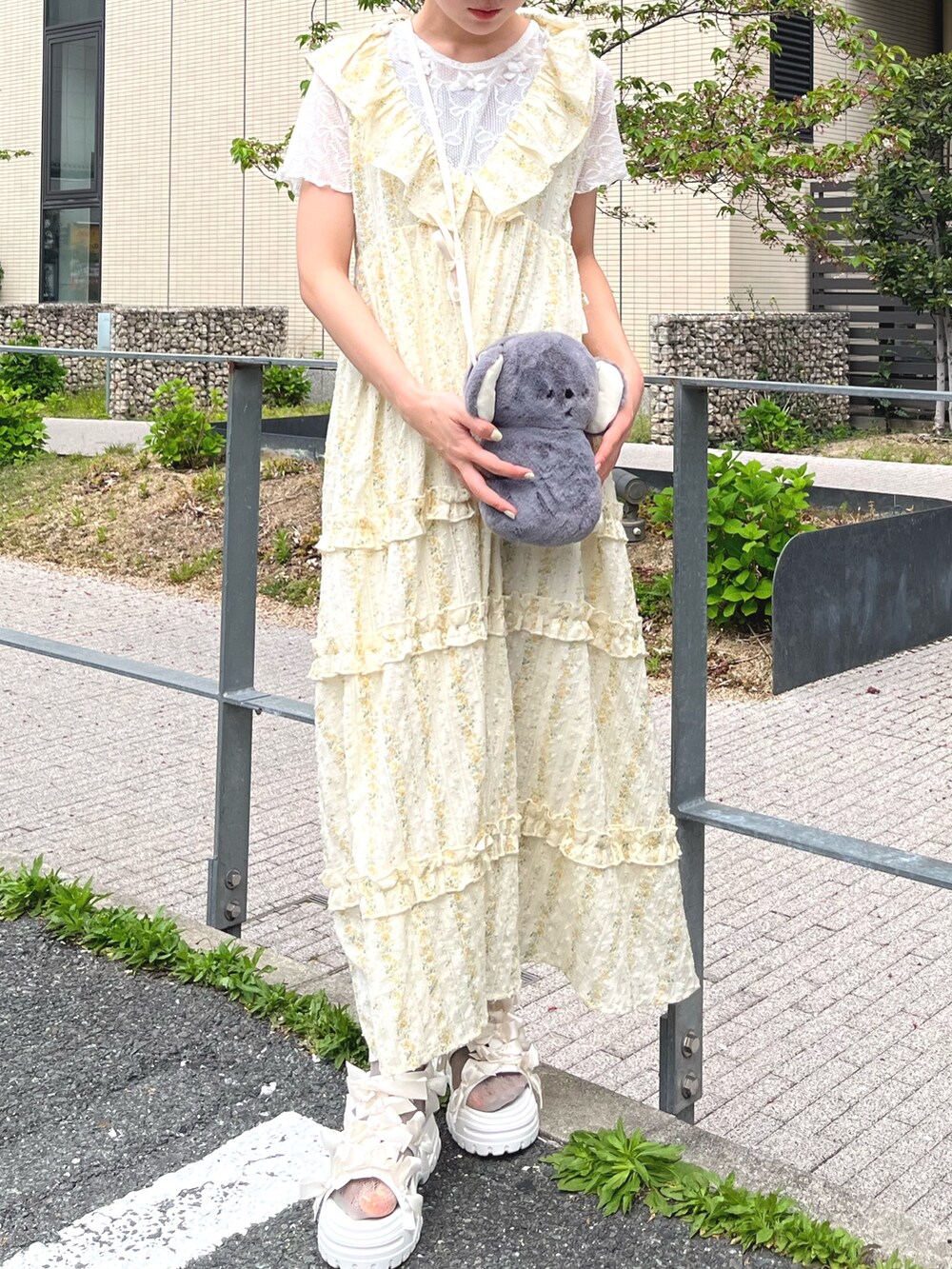 イエロー系のワンピース、ホワイト系のTシャツ/カットソー、グレー系のショルダーバッグを着用したレディースの春コーディネートの2枚目の写真