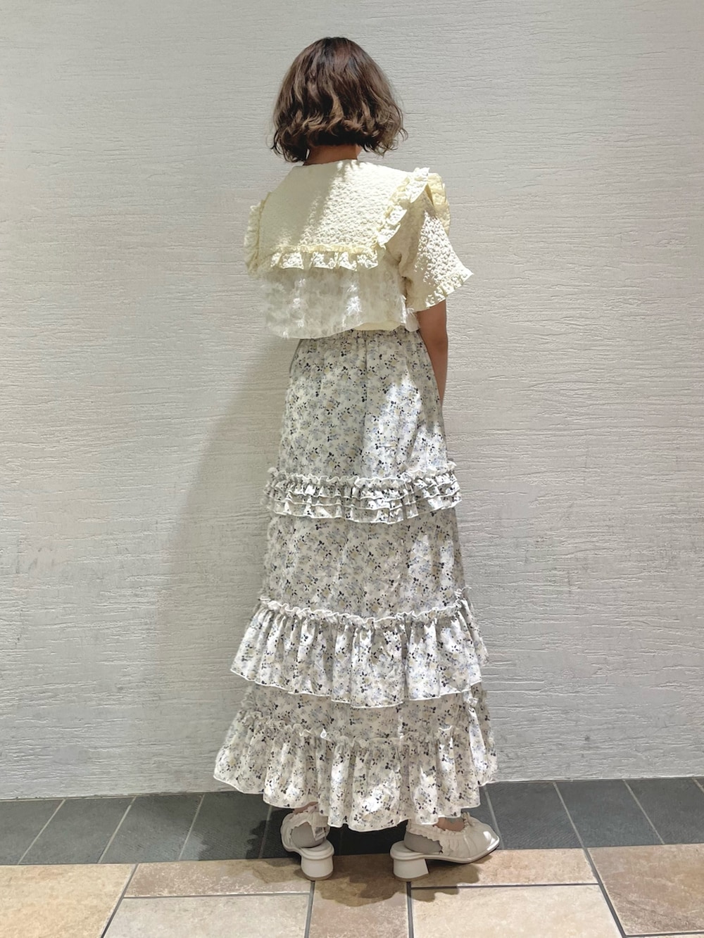 イエロー系のシャツ/ブラウス、ホワイト系のキャミソール、イエロー系のスカートを着用したレディースの夏コーディネートの4枚目の写真