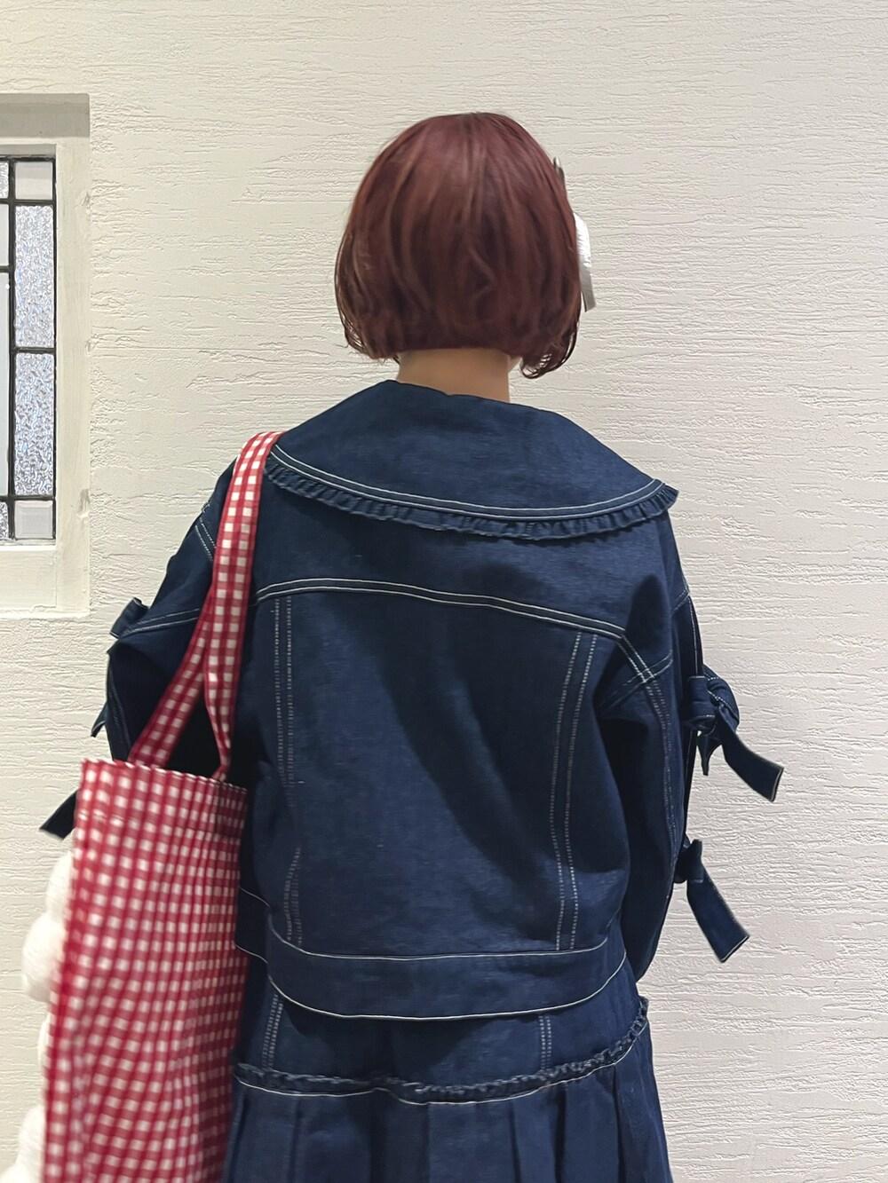 ブルー系のスカート、ブルー系のデニムジャケット、レッド系のトートバッグを着用したレディースの秋コーディネートの7枚目の写真