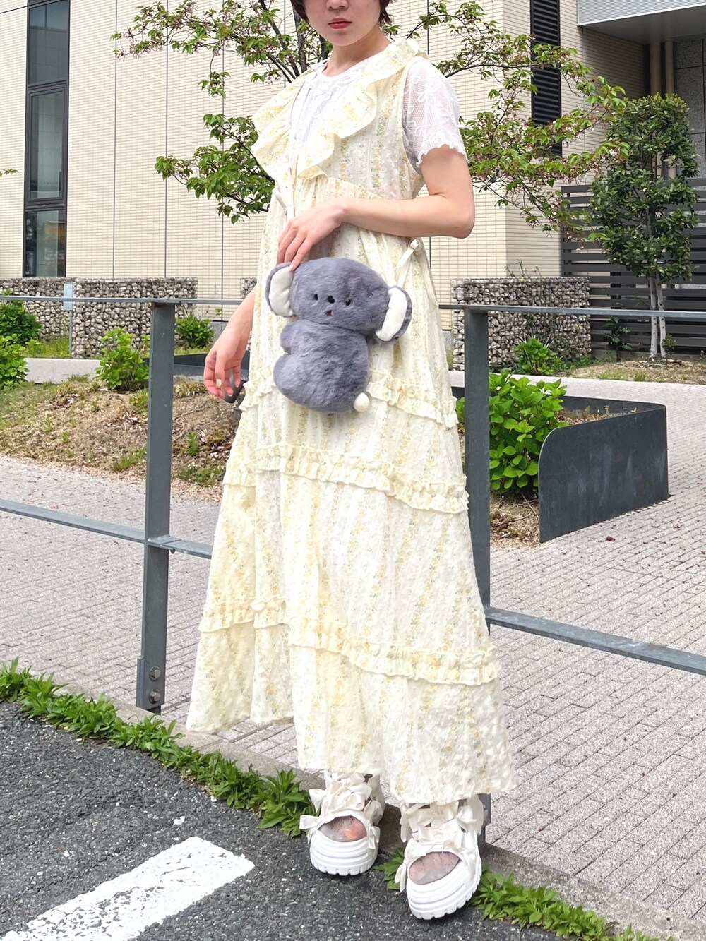 イエロー系のワンピース、ホワイト系のTシャツ/カットソー、グレー系のショルダーバッグを着用したレディースの春コーディネートの3枚目の写真