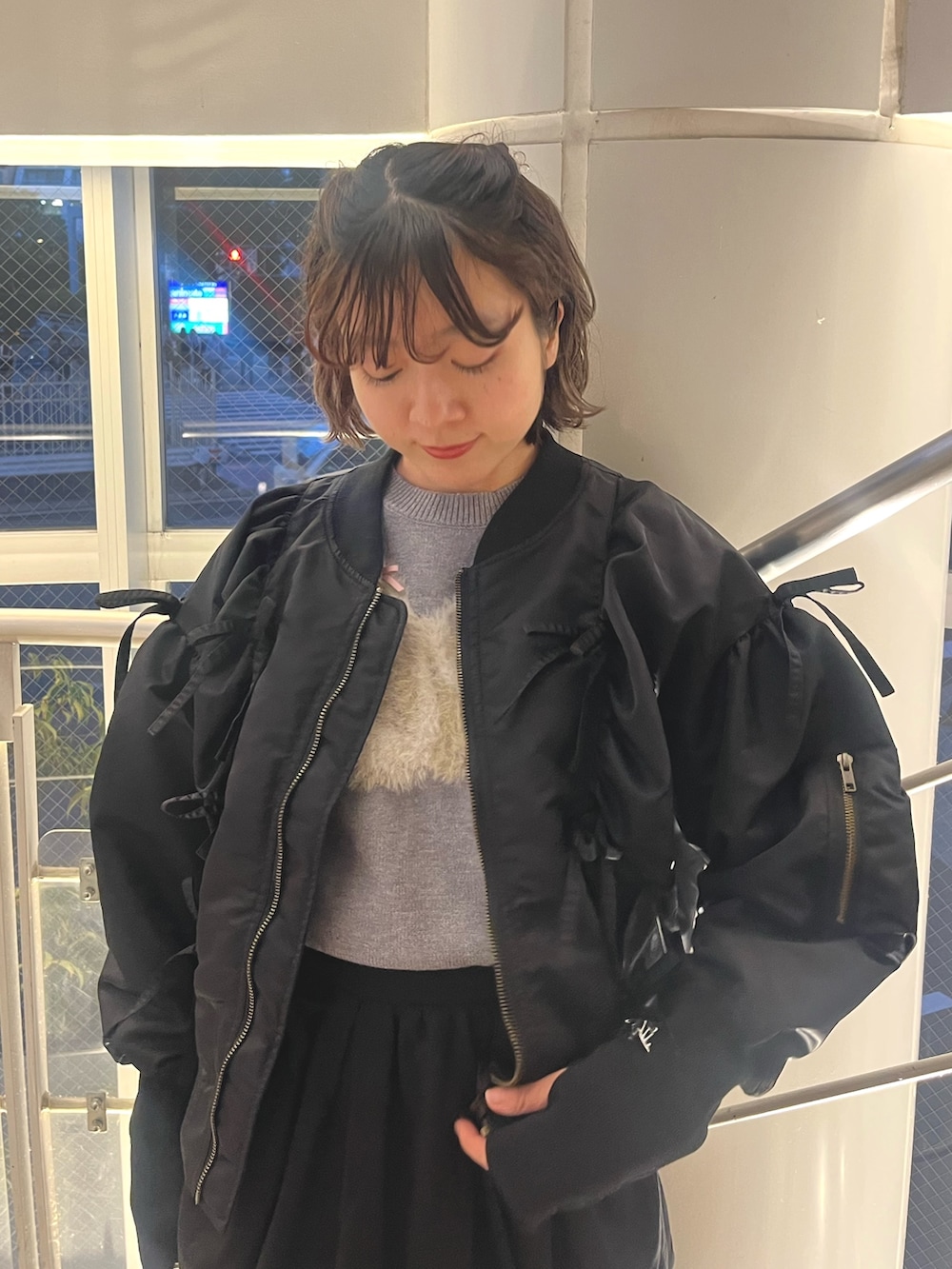 グレー系のニット/セーター、ブラック系のMA-1、ブラック系のスカートを着用したレディースの秋コーディネートの6枚目の写真