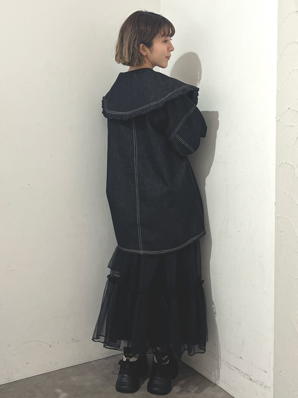 ホワイト系のトートバッグ、ブルー系のデニムジャケット、ブラック系のスカートを着用したレディースの秋コーディネートの5枚目の写真