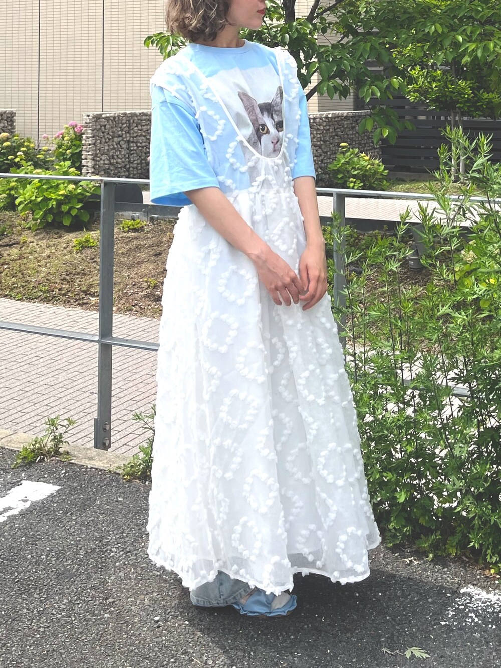 ホワイト系のジャンパースカート、ブルー系のTシャツ/カットソー、ブルー系のデニムパンツを着用したレディースの春コーディネートの2枚目の写真