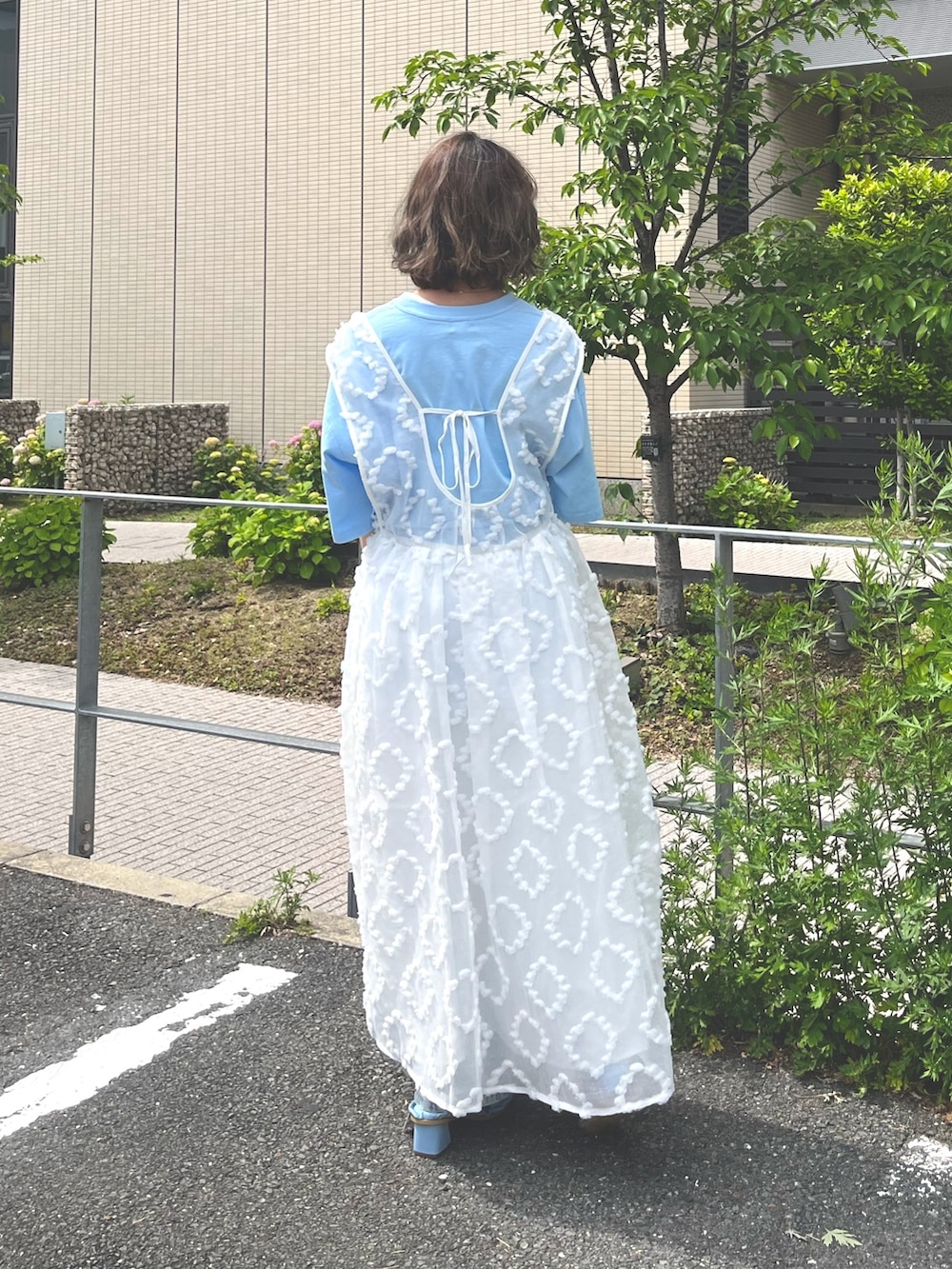 ホワイト系のジャンパースカート、ブルー系のTシャツ/カットソー、ブルー系のデニムパンツを着用したレディースの春コーディネートの3枚目の写真