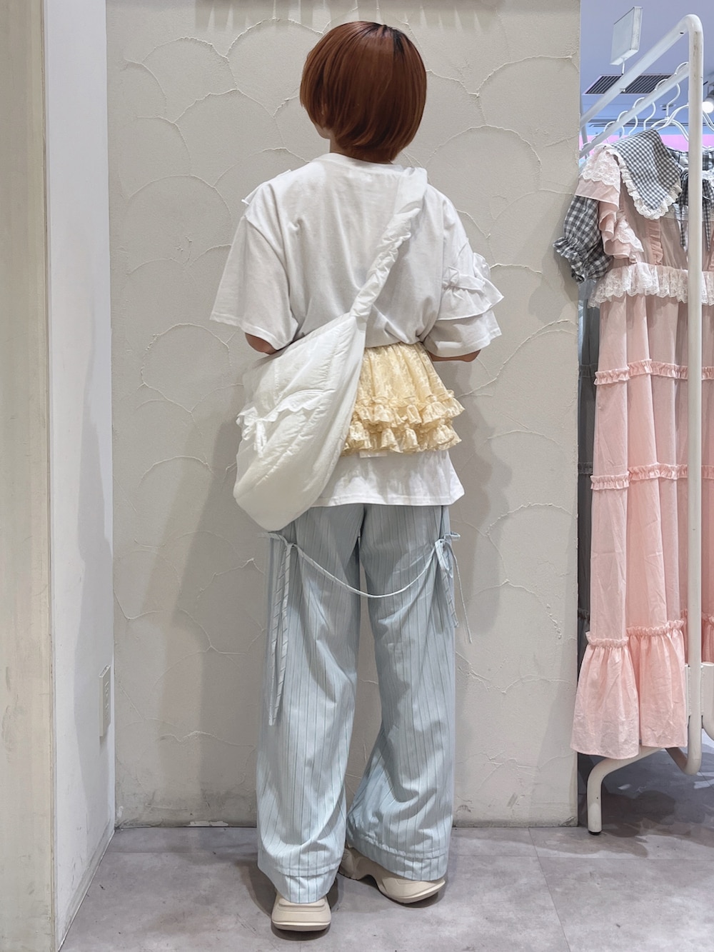 ホワイト系のショルダーバッグ、ホワイト系のTシャツ/カットソー、ブルー系のスラックスを着用したレディースの夏コーディネートの4枚目の写真