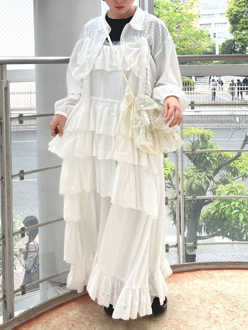 ブラック系のスニーカー、ブラック系のニット/セーター、ホワイト系のワンピースを着用したレディースの春コーディネートの4枚目の写真