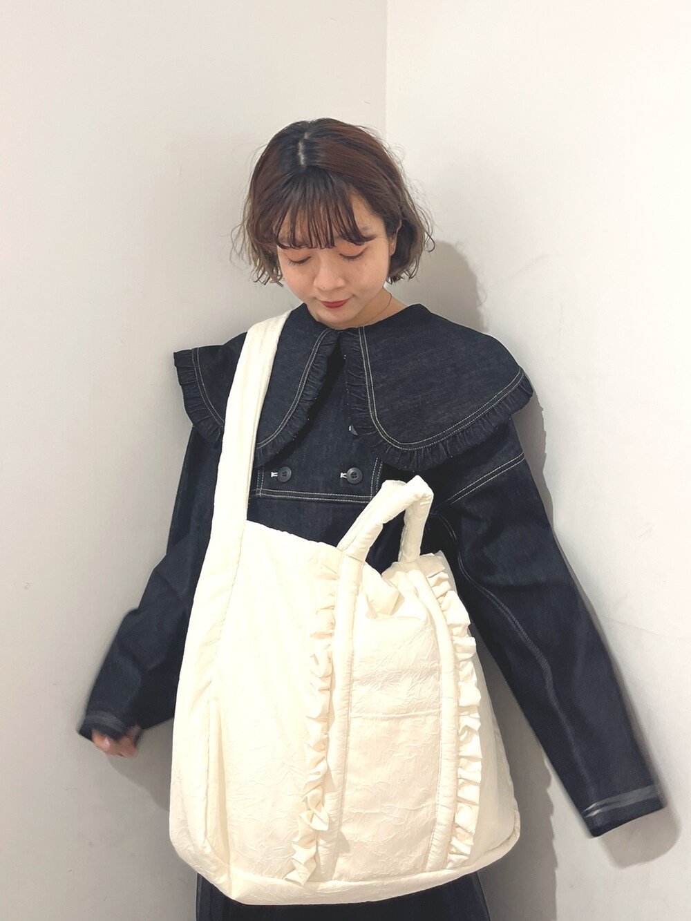 ホワイト系のトートバッグ、ブルー系のデニムジャケット、ブラック系のスカートを着用したレディースの秋コーディネートの6枚目の写真