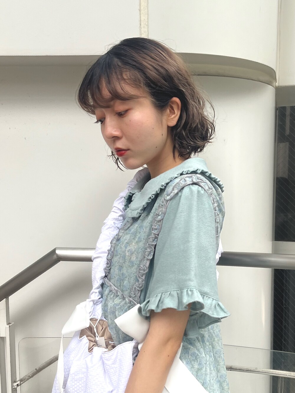 ホワイト系のショルダーバッグ、ブルー系のワンピース、グリーン系のワンピースを着用したレディースの夏コーディネートの5枚目の写真