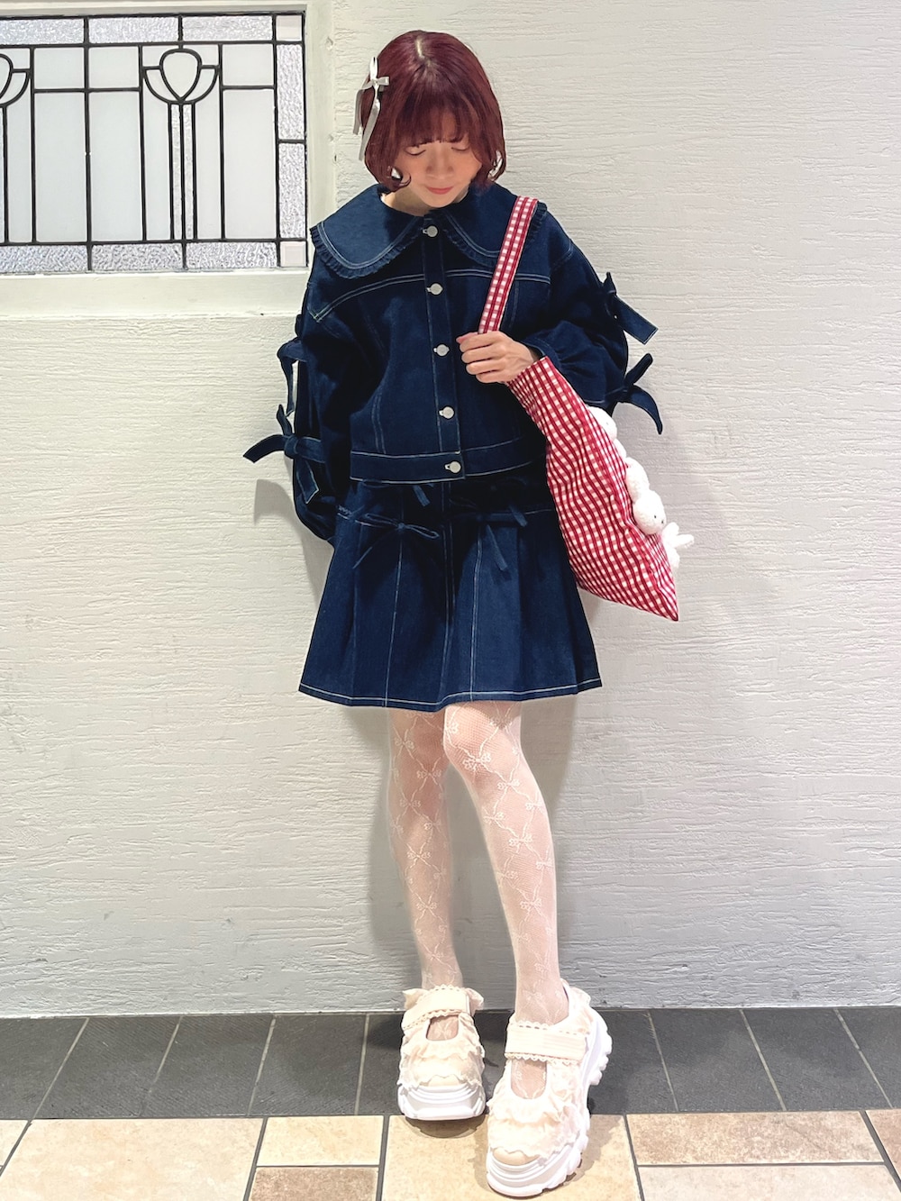 ブルー系のスカート、ブルー系のデニムジャケット、レッド系のトートバッグを着用したレディースの秋コーディネートの2枚目の写真