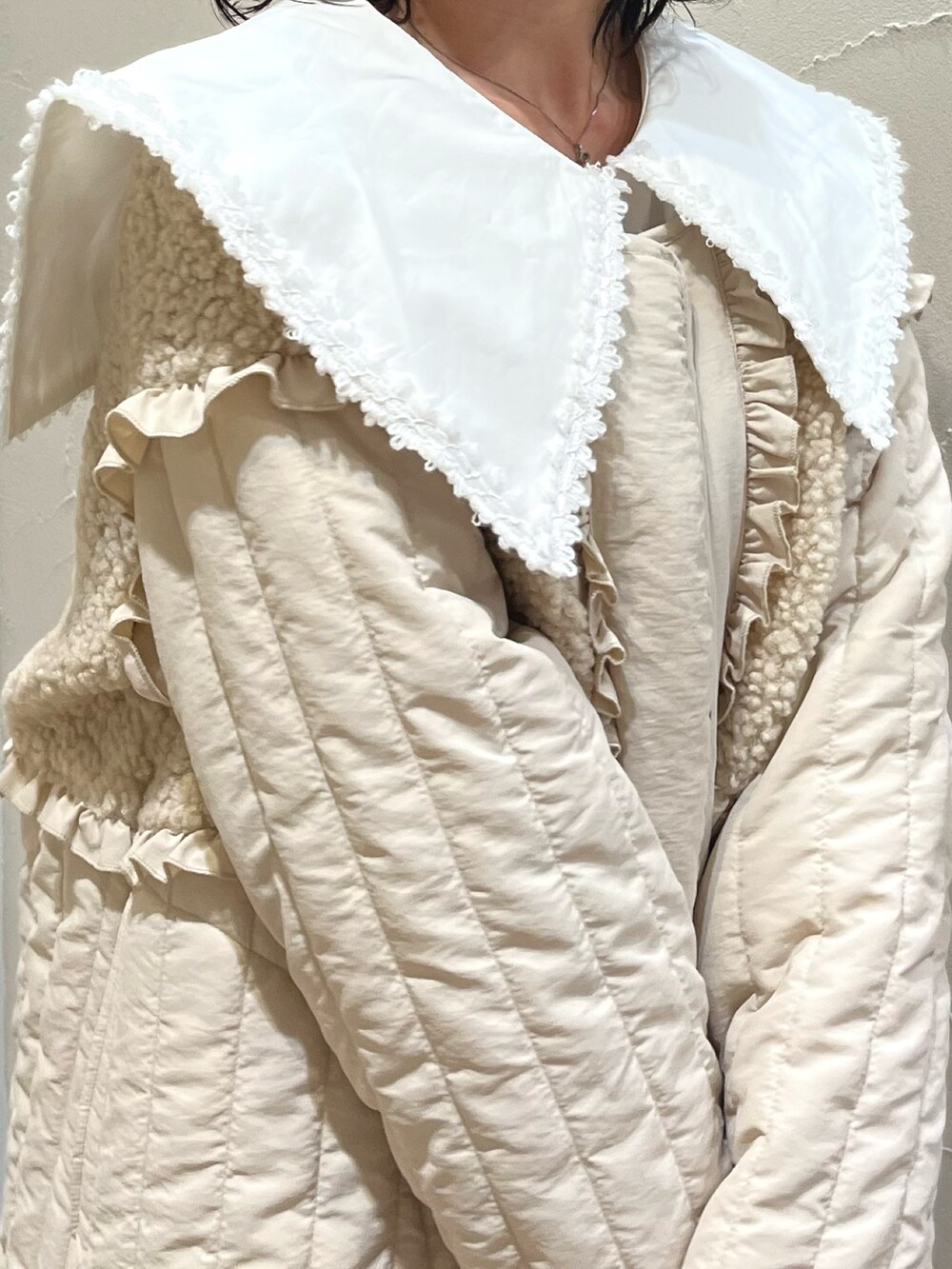 ホワイト系のステンカラーコート、グリーン系のスカート、ブラウン系のブーツを着用したレディースの秋コーディネートの3枚目の写真