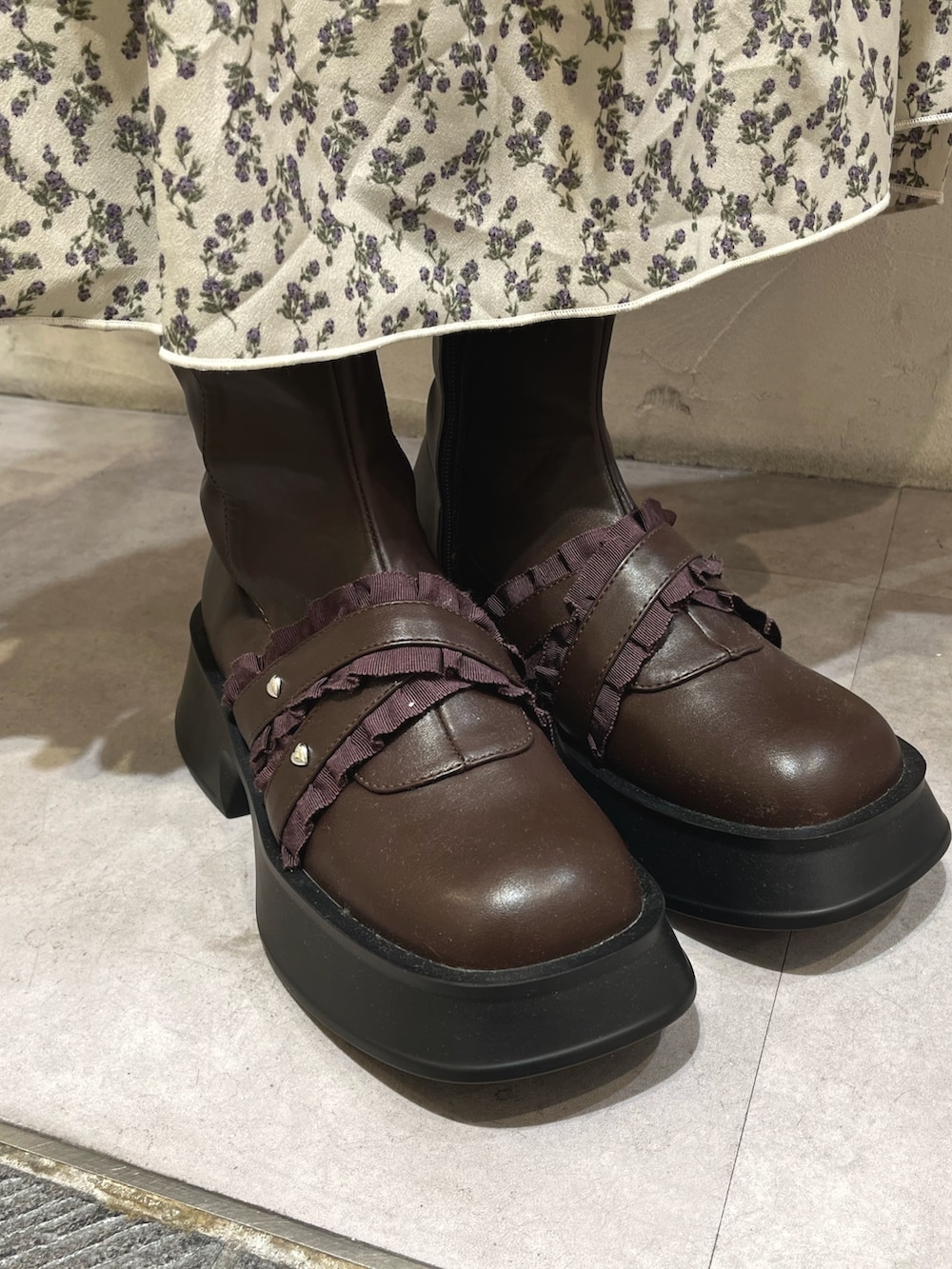 ホワイト系のステンカラーコート、グリーン系のスカート、ブラウン系のブーツを着用したレディースの秋コーディネートの6枚目の写真