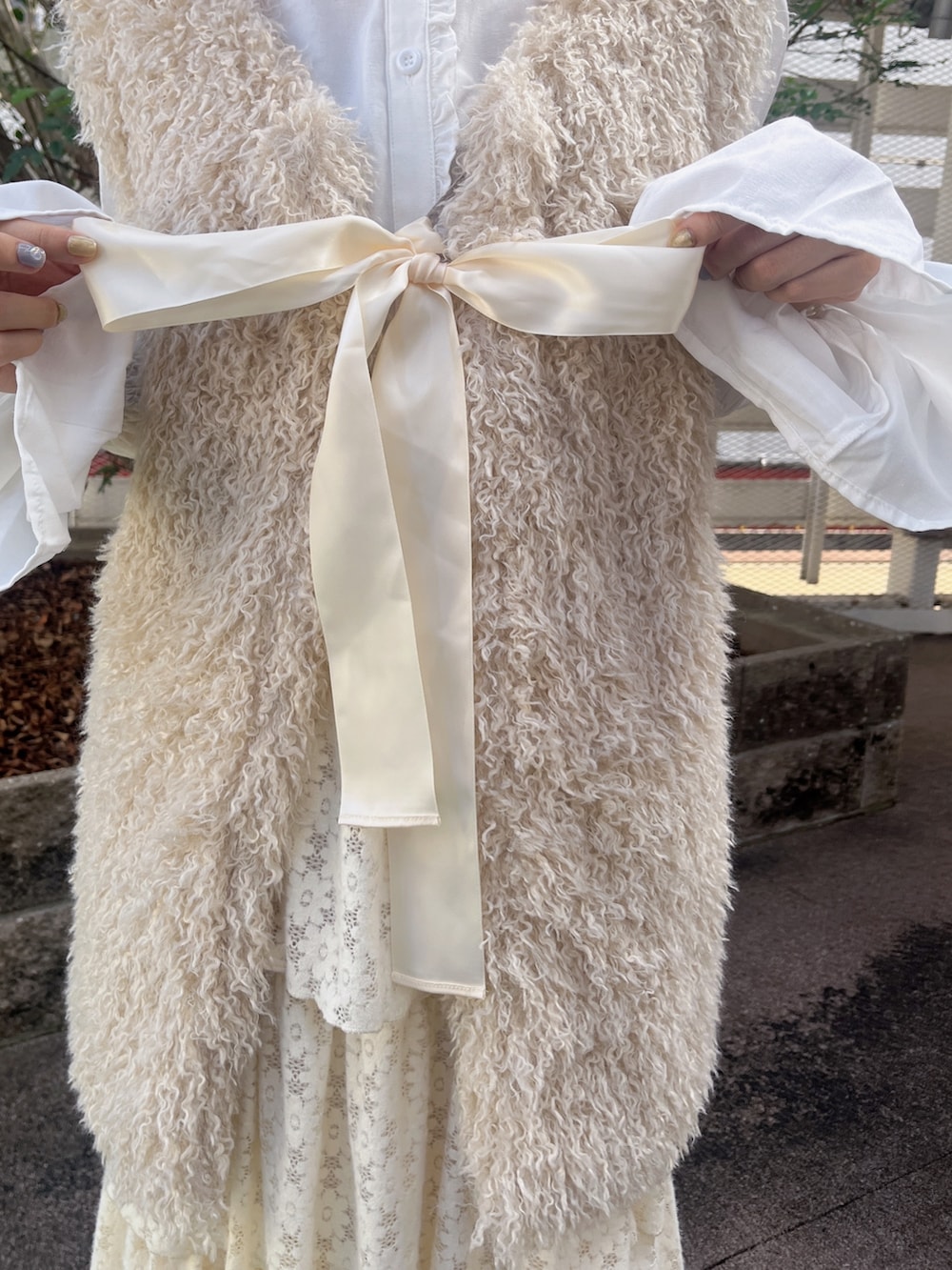 ベージュ系のダウンベスト、ホワイト系のシャツ/ブラウス、ホワイト系のスカートを着用したレディースの秋コーディネートの5枚目の写真