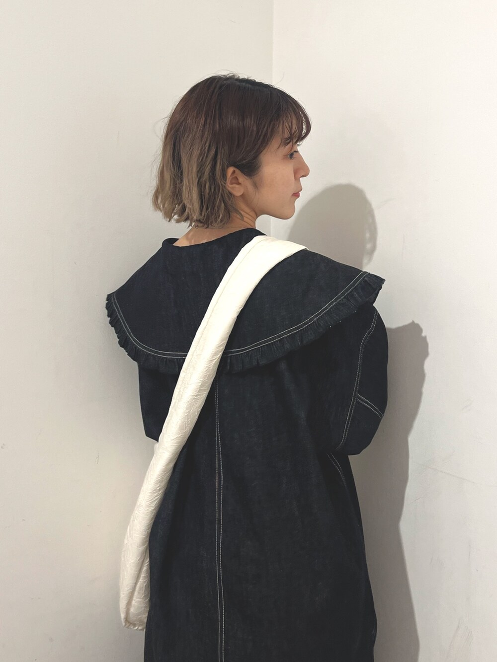 ホワイト系のトートバッグ、ブルー系のデニムジャケット、ブラック系のスカートを着用したレディースの秋コーディネートの8枚目の写真